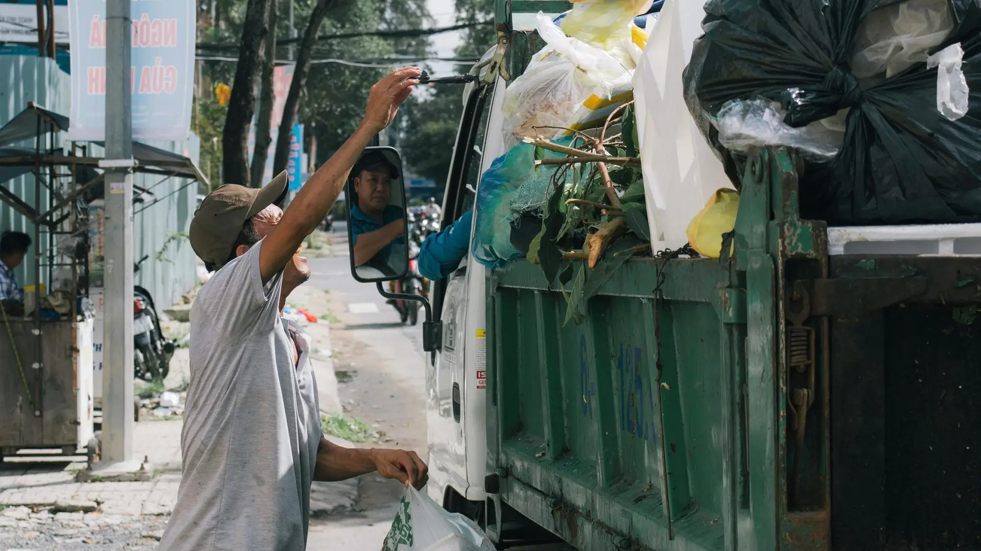 Sanitation worker collects trash from a street in an urban environment, showcasing daily waste management.