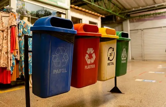 Four recycling bins for paper, plastic, metal, and glass indoors.